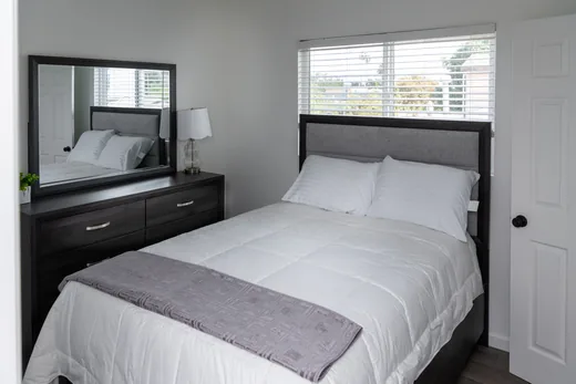 Third bedroom with a dark wood bed frame and mirrored dresser