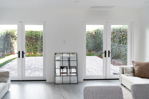 Double French doors opening to a paved, fenced patio